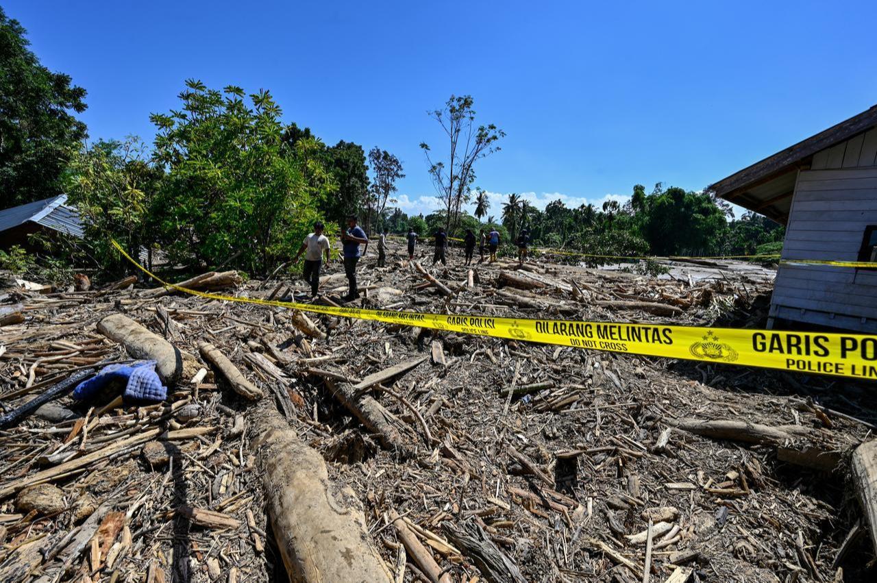 People walk across mud and debris in a flood-affected area in Aceh, Indonesia, November 30, 2025. (AFP Photo)