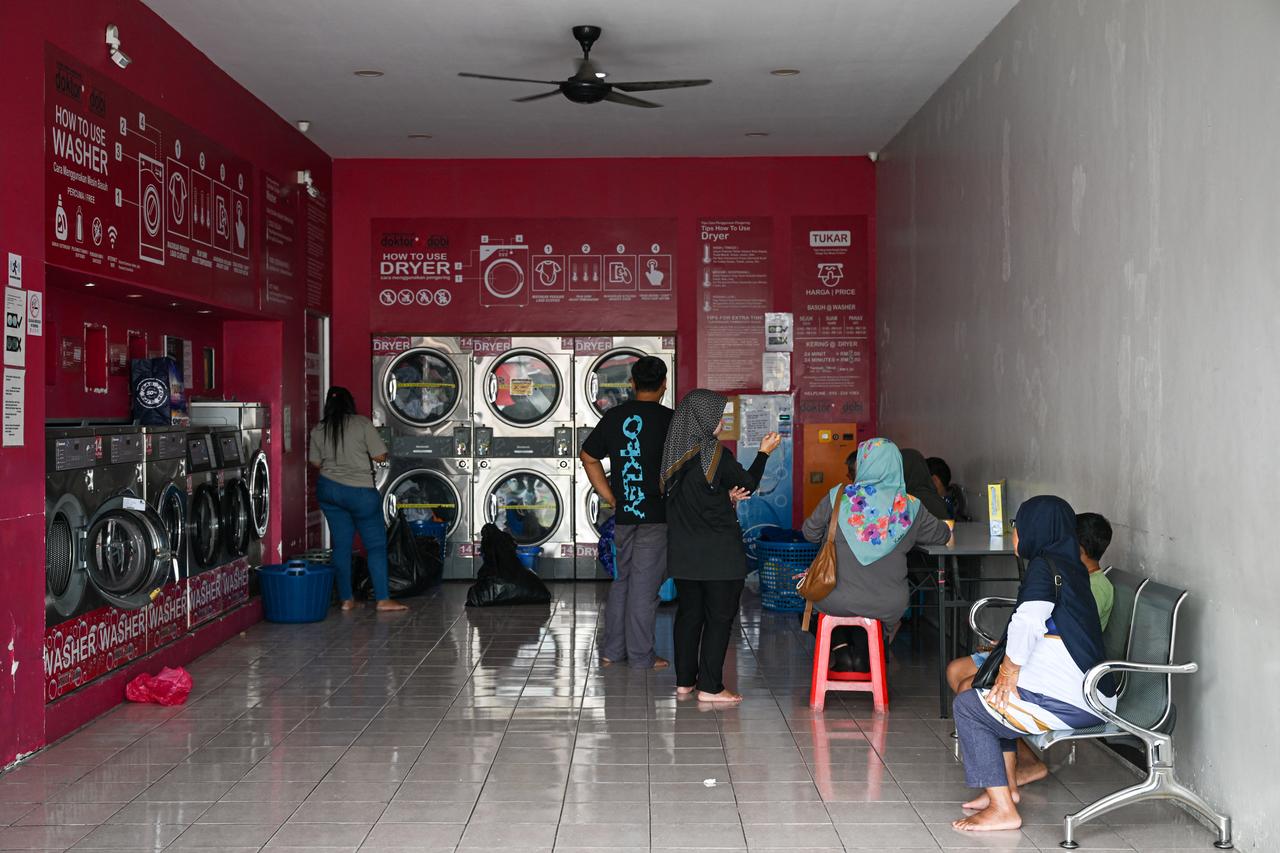 People queue to use coin-operated dryers at a laundromat in Karak, Malaysia’s Pahang state, November 29, 2025. (AFP Photo)