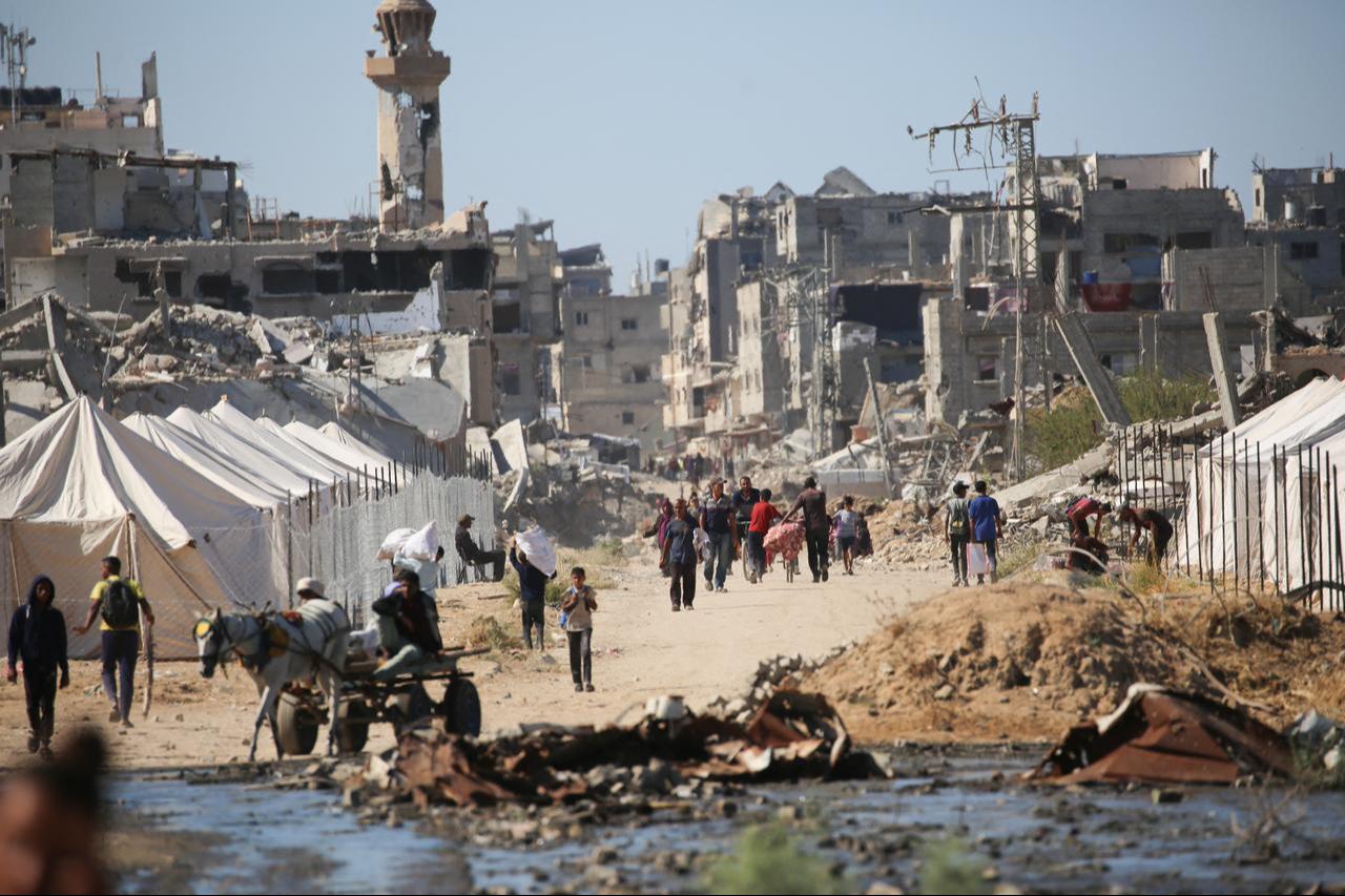 Displaced Palestinians walk past tents and destroyed buildings as they return to their homes in al-Zahra area, north of Nuseirat refugee camp, in central Gaza Strip, Oct. 14, 2025. (AFP Photo)