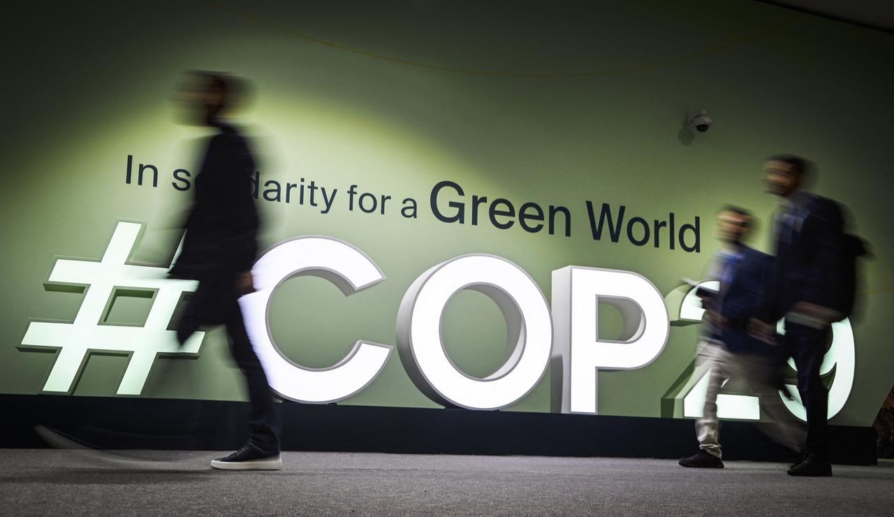 People walk past the logotype at the venue for the 2024 United Nations Climate Change Conference (COP29) in Baku, Azerbaijan, on Nov. 11, 2024. (AFP Photo)