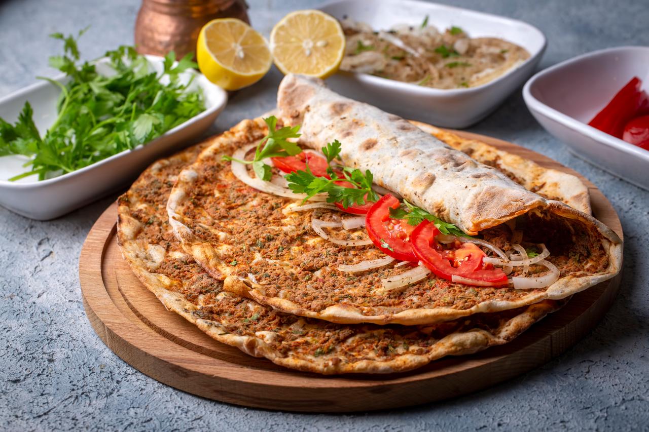Lahmacun served rolled with fresh tomato, onion, and parsley─many diners add lemon juice before rolling to brighten the flavors. (Adobe Stock Photo)