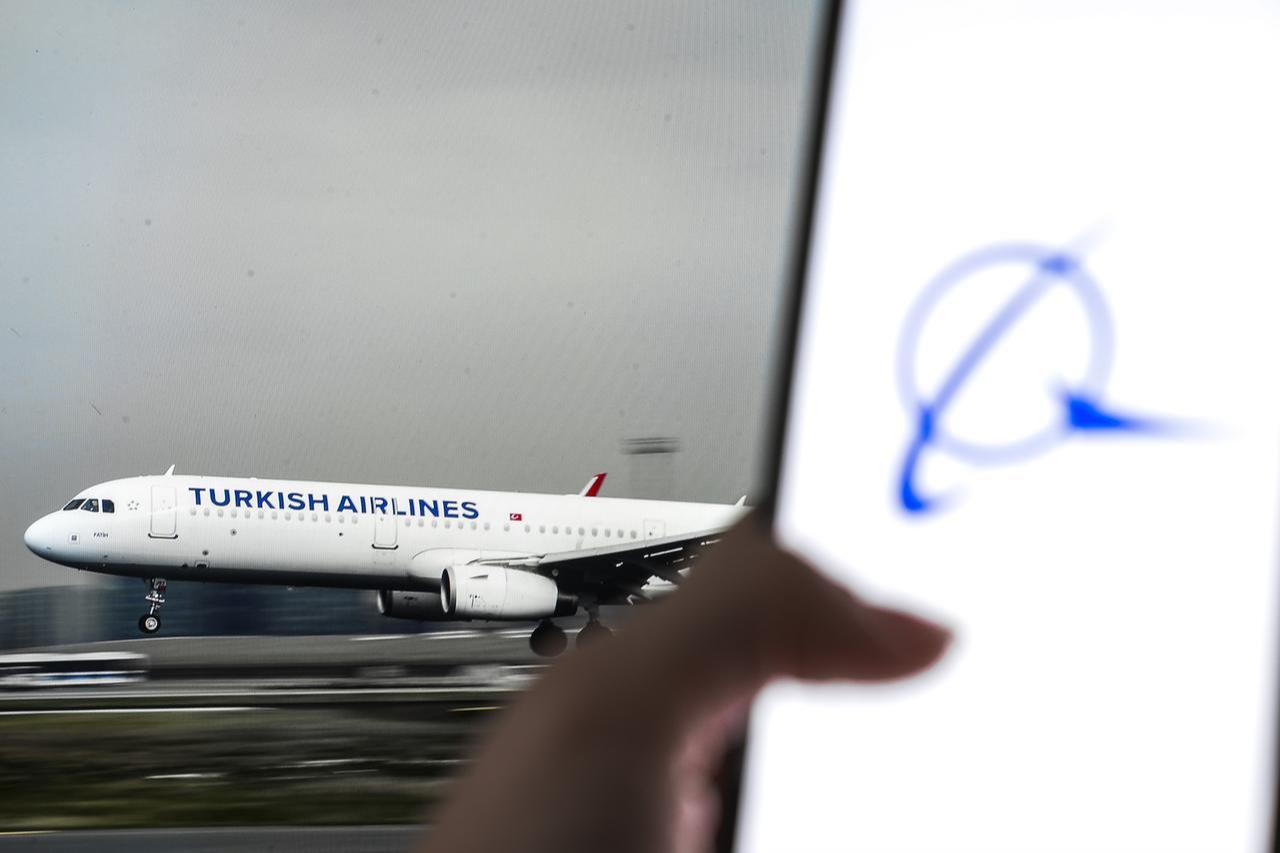In this photo illustration, a Turkish Airlines plane is displayed on a screen behind the Boeing logo is displayed on a mobile phone in Ankara, Türkiye, on Sept. 26, 2025. (AA Photo)