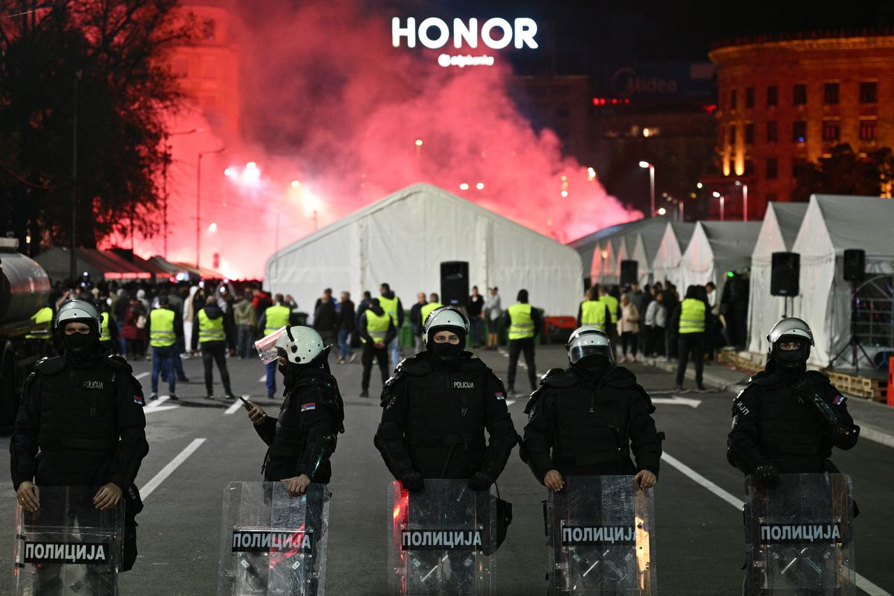 Sırp çevik kuvvet polisi, 5 Kasım 2025'te sağcı hükümete karşı muhalefetin Balkan ülkesi Belgrad Sırbistan'ı sarsmaya devam ettiği bir yıl boyunca, Sırbistan parlamento binasının önünde ışıklı işaret fişeklerinin arkasında hükümet destekçileri olarak hükümet karşıtı protestocularla karşı karşıya. (AFP Fotoğrafı)