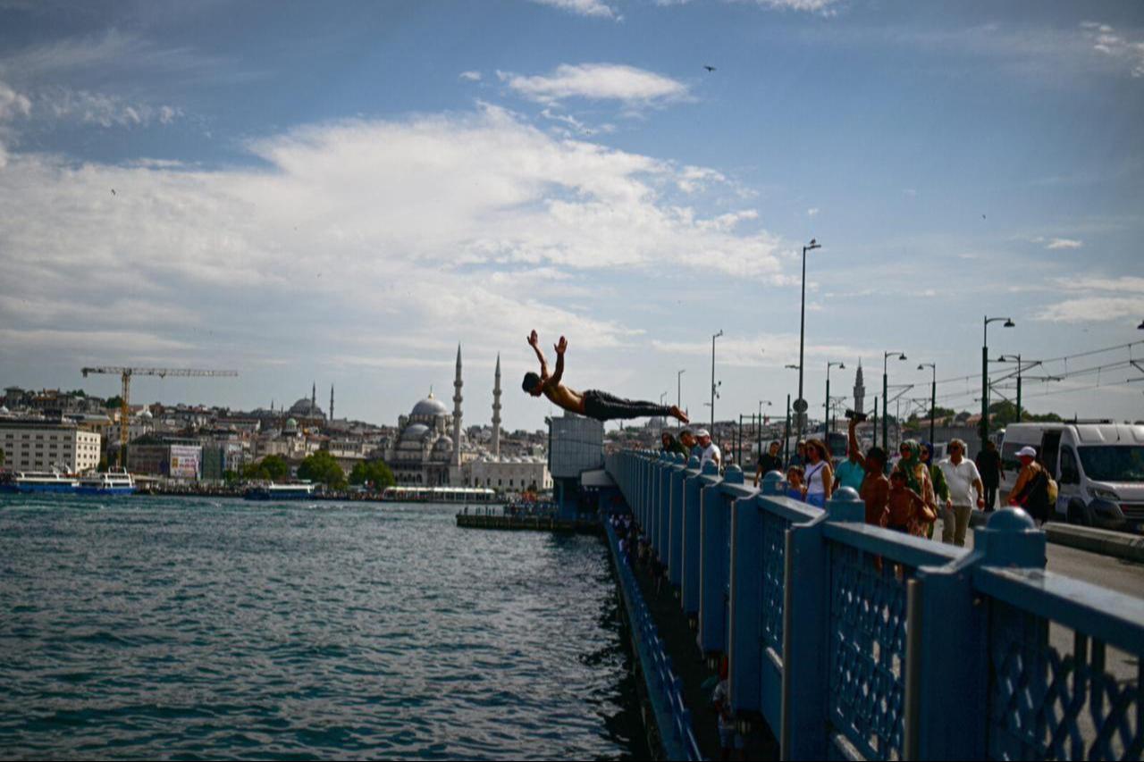 A boy jumps into the sea at the shore of Karakoy as people are overwhelmed by the hot weather and humidity and try to cool off themselves, Istanbul, Türkiye, July 16, 2024. (AA Photo)