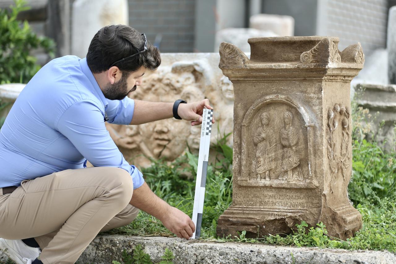Archeologist Ahmet Meke examines a human-shaped grave stele in the form of an altar, discovered by a shepherd grazing his goats in Seydikemer district and placed under protection, will be exhibited in a museum in Mugla, Türkiye, Nov. 28, 2025. (AA Photo)