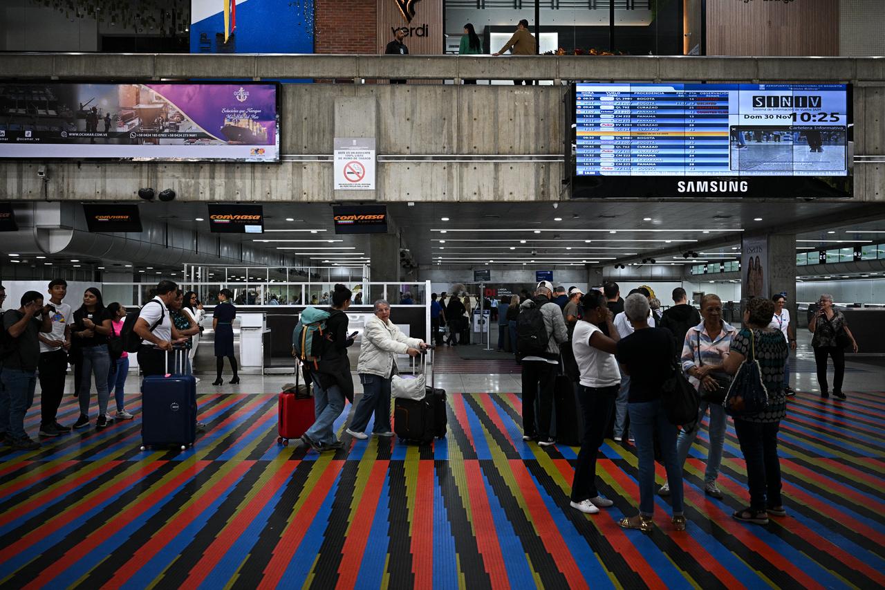 Passengers queue at a counter at the Simon Bolivar International Airport in Maiquetia, La Guaira State, Venezuela, on November 30, 2025. (AFP Photo)