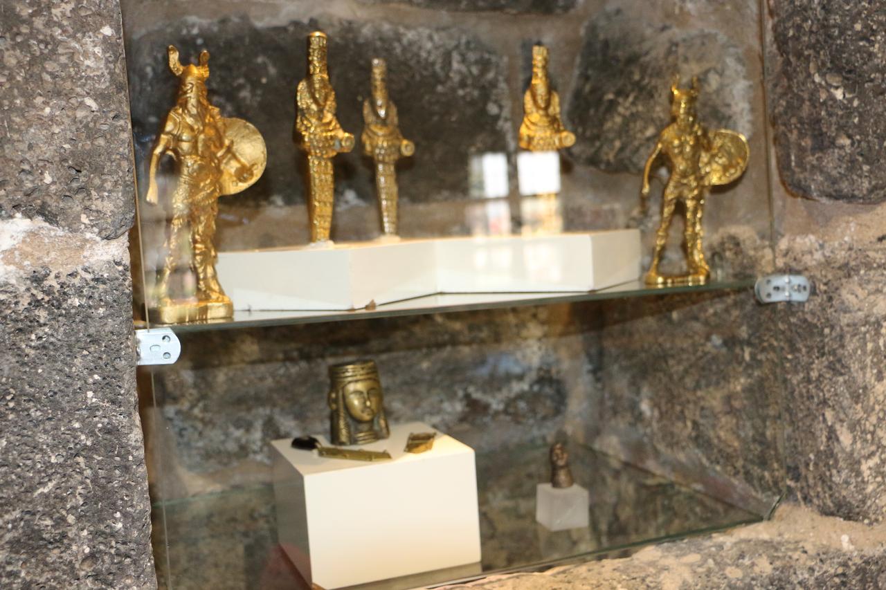 Counterfeit gold-colored figurines and imitation sculptural pieces showcased on glass shelves within the fake-artifact exhibition, Dec. 1, 2025. (IHA Photo)