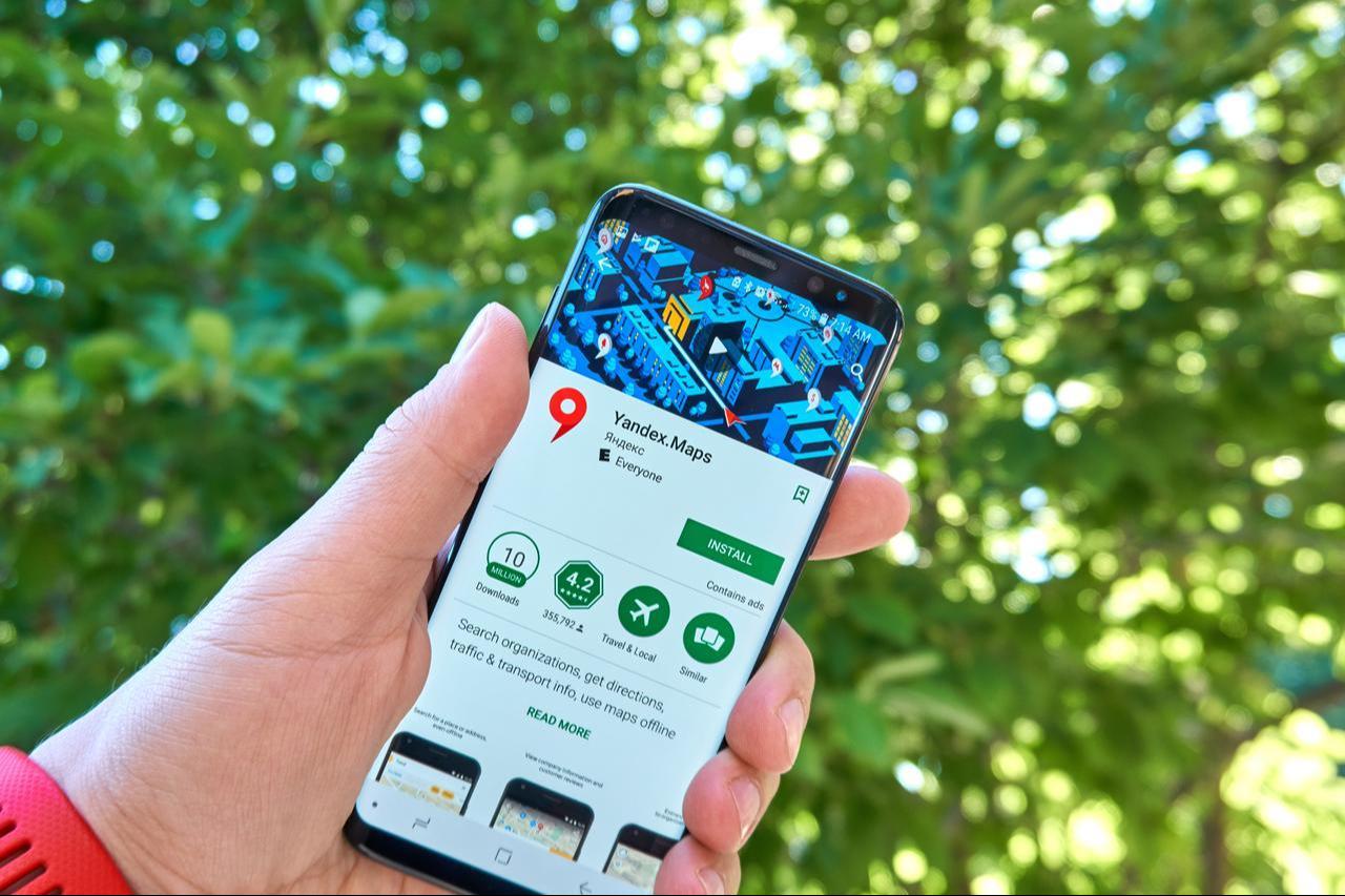 A person holds a smartphone displaying the Yandex Maps app download page on Google Play. (Adobe Stock Photo)