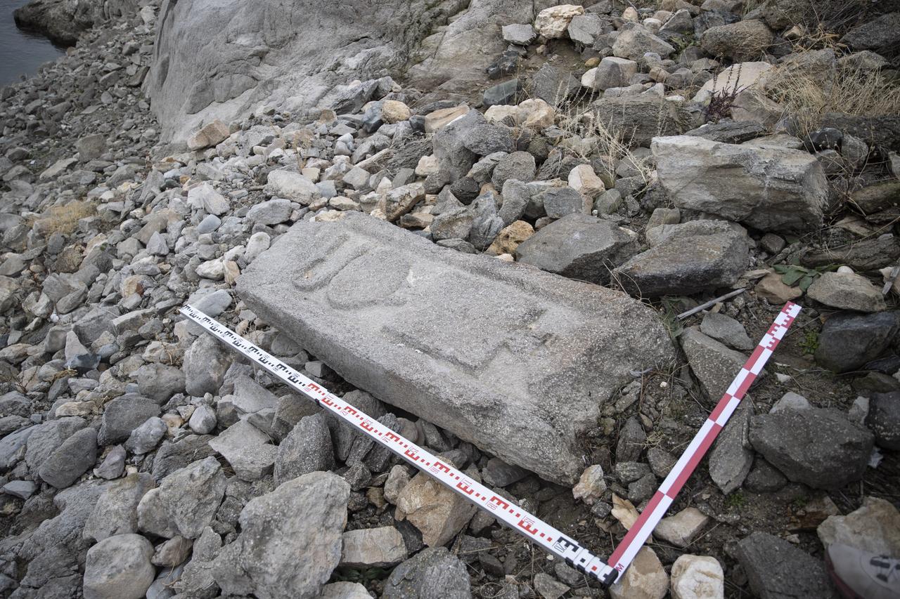 A grave-chest fragment lies exposed on the rocky shore of Pertek Fortress after the water level of Keban Dam Lake fell significantly in Tunceli, Türkiye, Dec. 11, 2025. (AA Photo)