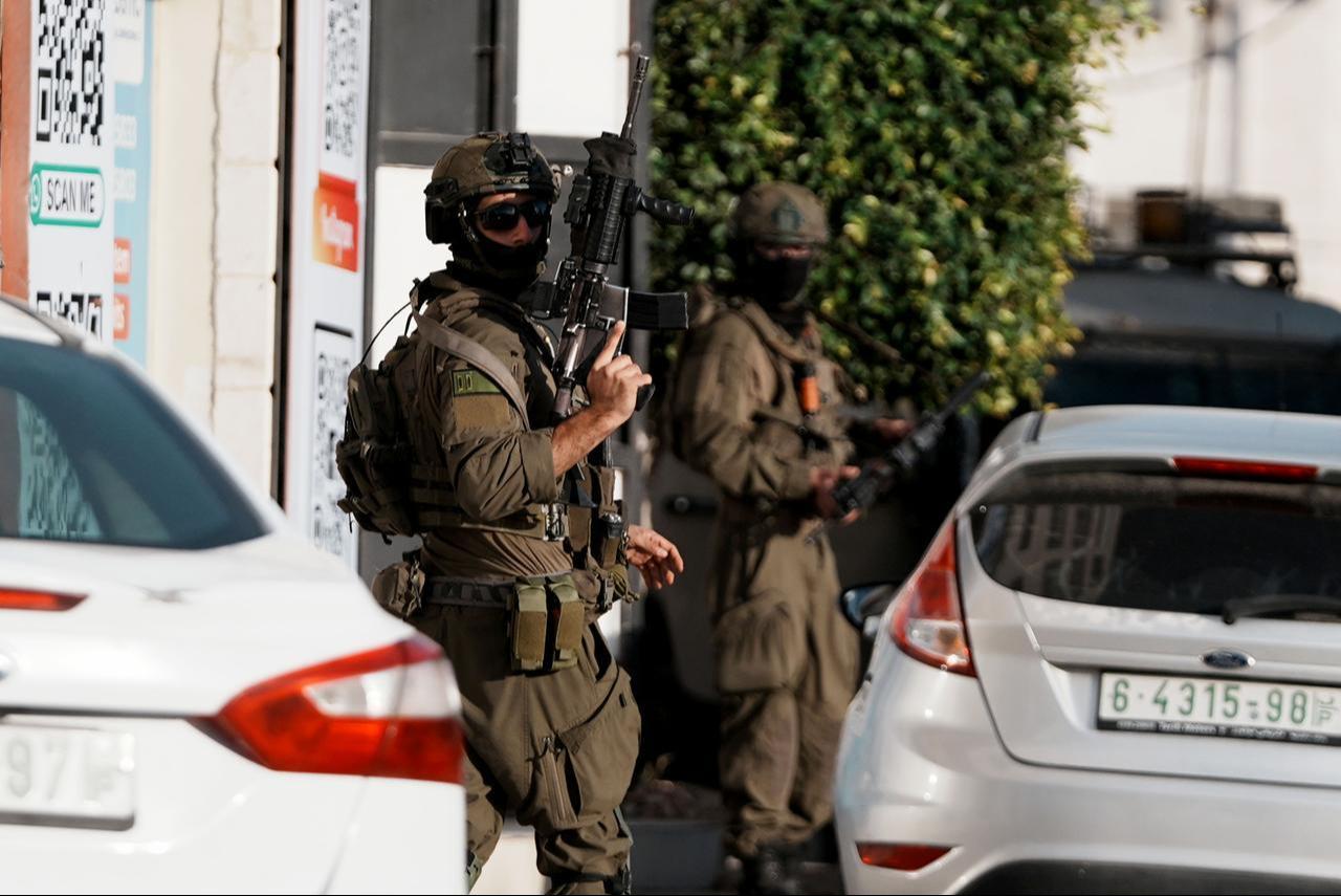 Israeli soldiers take positions near parked vehicles around Ali bin Abi Talib Mosque during a raid, in Al Bireh, West Bank, Dec. 9, 2025. (AA Photo)