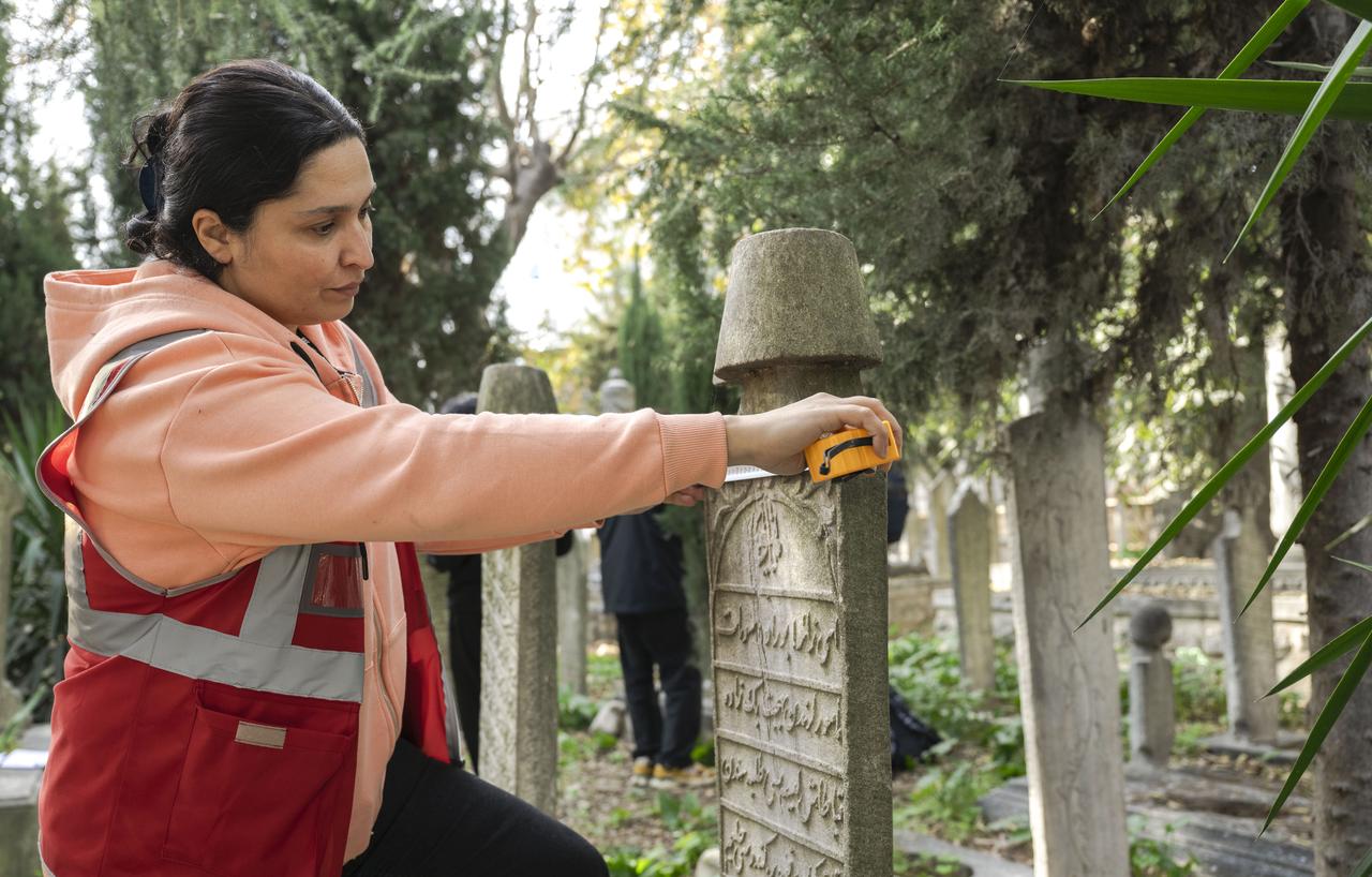 An expert measures the dimensions of an Ottoman tombstone to be added to the digital archive during fieldwork at Seyh Devati Mustafa Efendi Mosque cemetery in Uskudar, Istanbul, Türkiye, Dec. 11, 2025. (AA Photo)