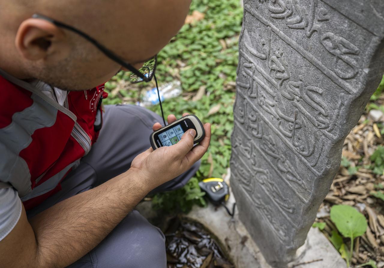 A researcher logs GPS coordinates of an inscriptioned tombstone for Türkiye’s new digital heritage database at Seyh Devati Mustafa Efendi Mosque cemetery in Uskudar, Istanbul, Türkiye, Dec. 11, 2025. (AA Photo)