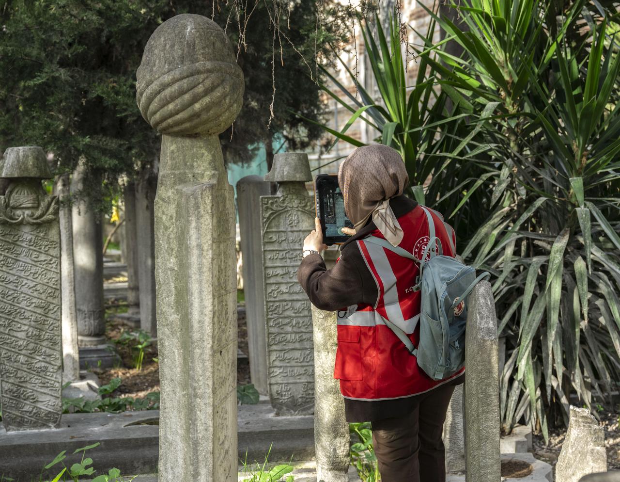 A team member records the details of a historic gravestone using a tablet as part of the nationwide tombstone inventory initiative at Seyh Devati Mustafa Efendi Mosque cemetery in Uskudar, Istanbul, Türkiye, Dec. 11, 2025. (AA Photo)
