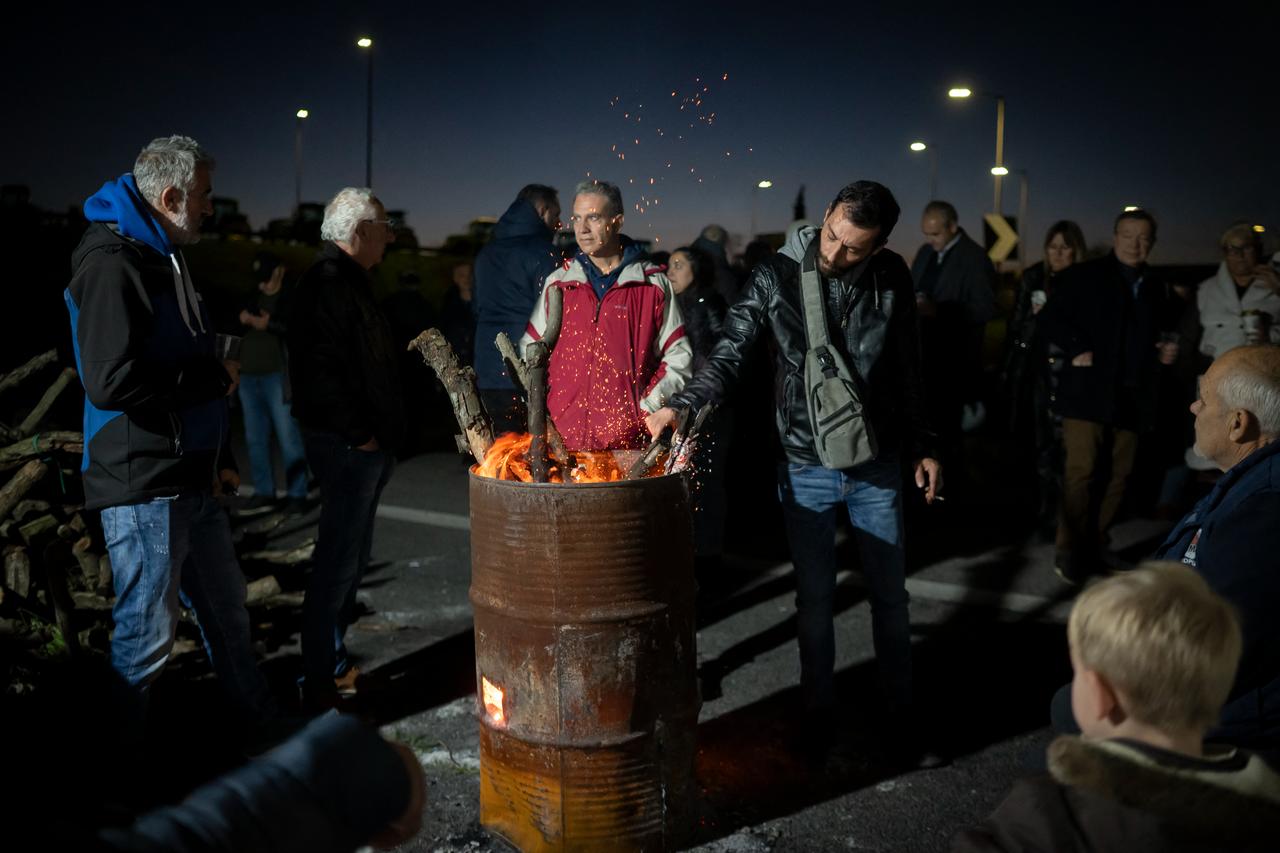 Farmers gather around a fire to warm themselves during a protest blocking a national highway with tractors, on the outskirts of Larissa, Greece, December 9, 2025. (AFP Photo)