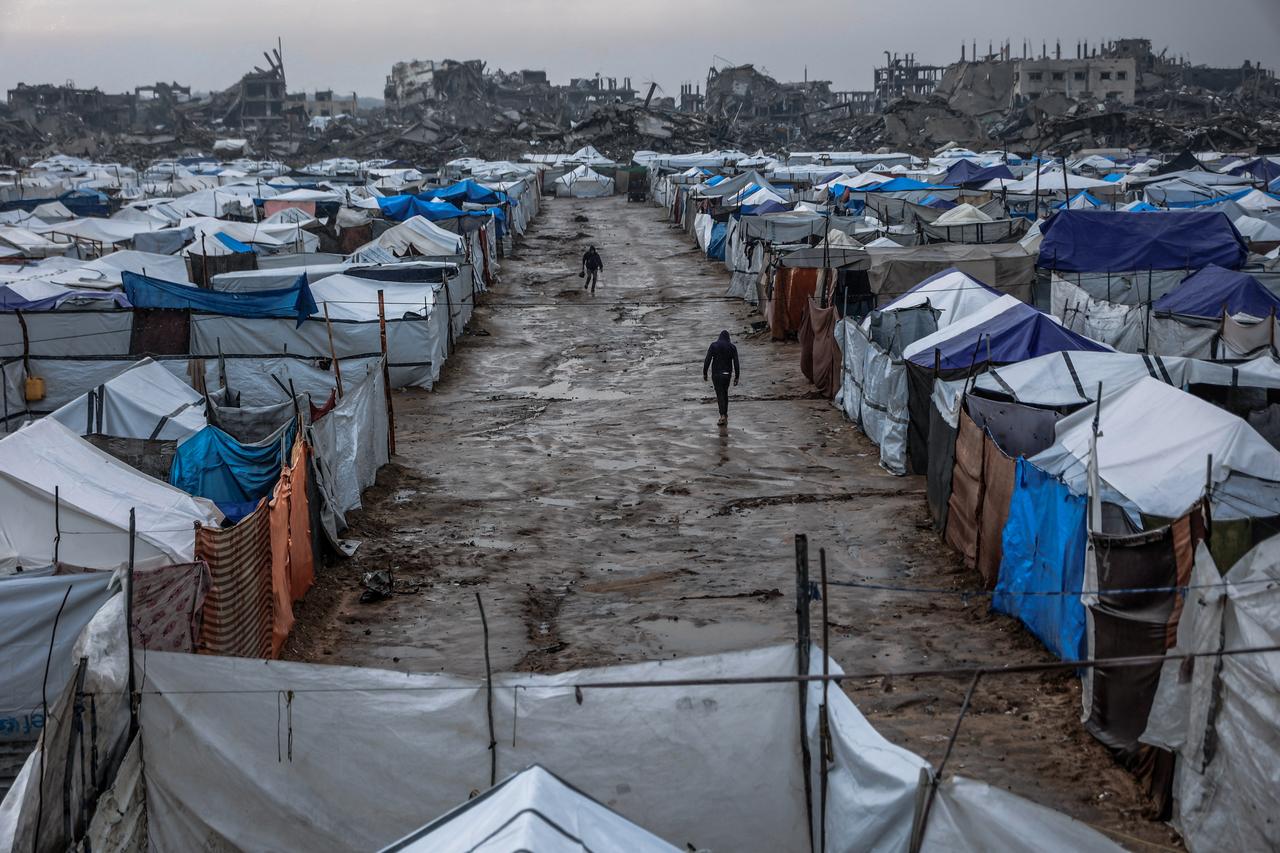 Men walk along a muddy alley at a makeshift camp sheltering displaced Palestinians after heavy rains in the Zeitoun neighbourhood of Gaza City, Dec. 11, 2025. (AFP Photo)