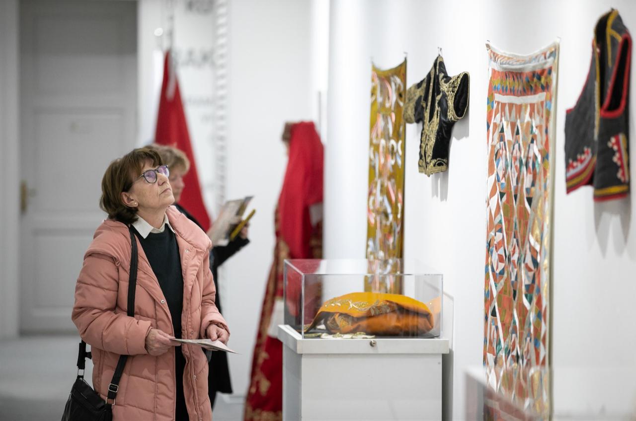 A visitor examines embroidered vests and textile panels inspired by Turkish wedding traditions at the exhibition at the Yunus Emre Institute in Zagreb, Croatia, Dec. 11, 2025. (AA Photo)