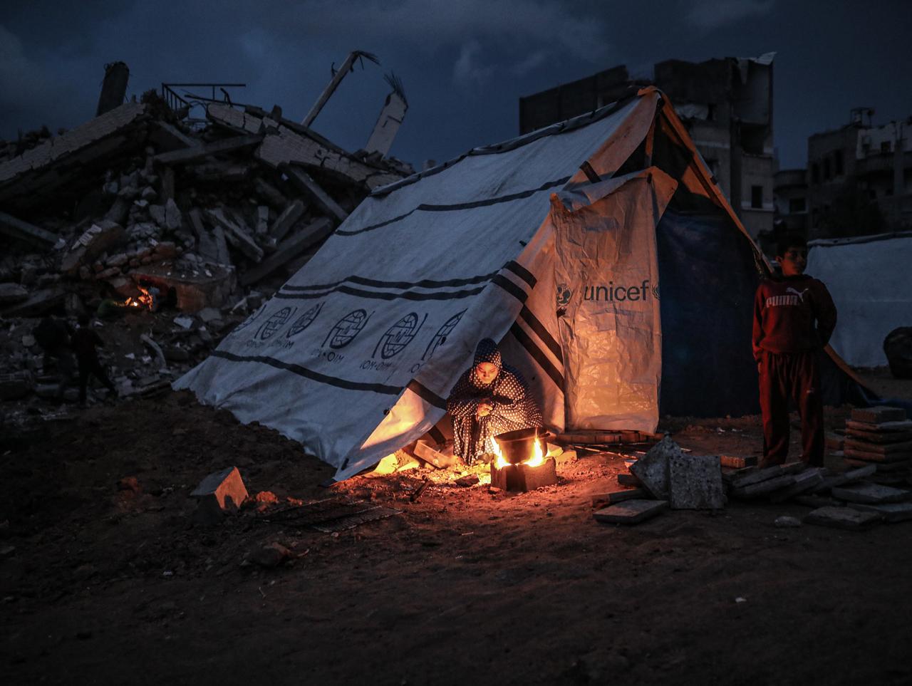 Displaced Palestinian children warm themselves around an open fire in makeshift tents east of Bureij Refugee Camp in central Gaza on Dec. 10, 2025. (AA Photo)