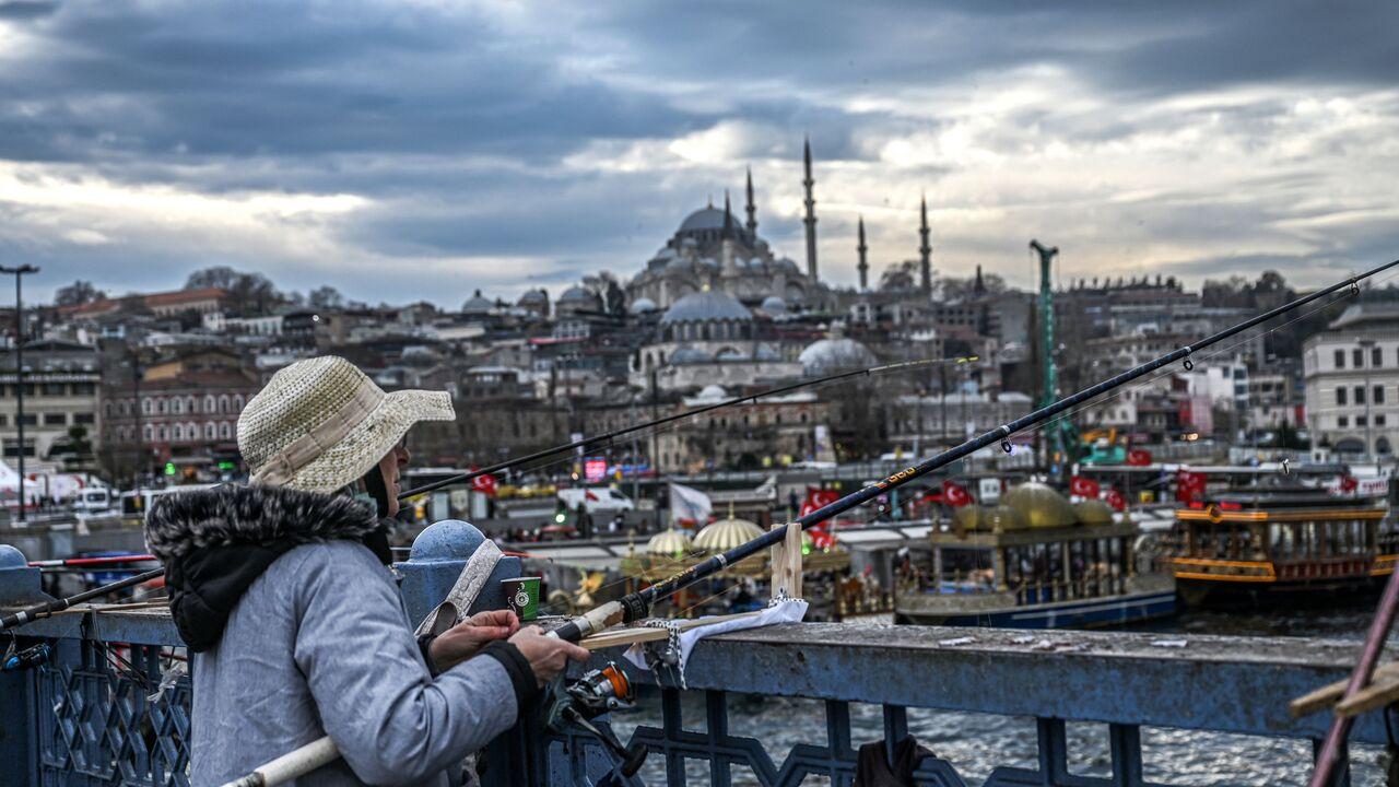 People fish from the Galata bridge, near Suleymaniye mosque (backround) in the Eminonu district of Istanbul, Türkiye on Jan. 10, 2023. (AFP Photo)