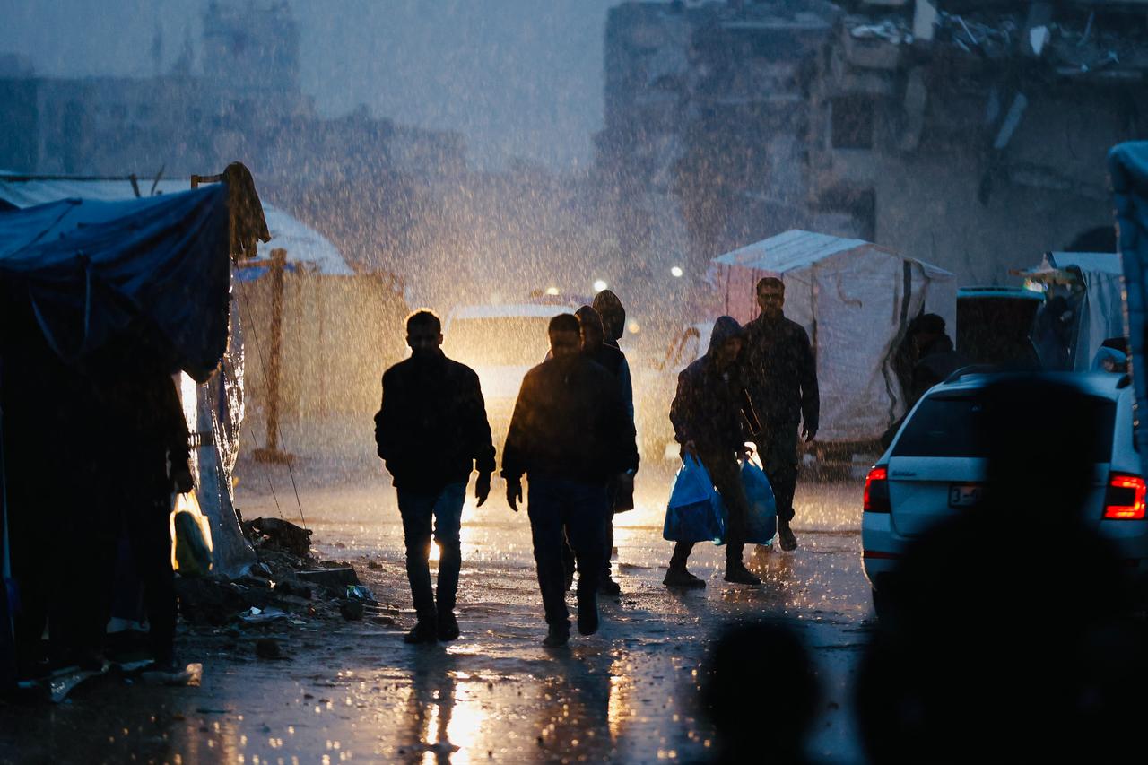 Displaced Palestinians walk in the rain in Gaza City on December 15, 2025. (AFP Photo)