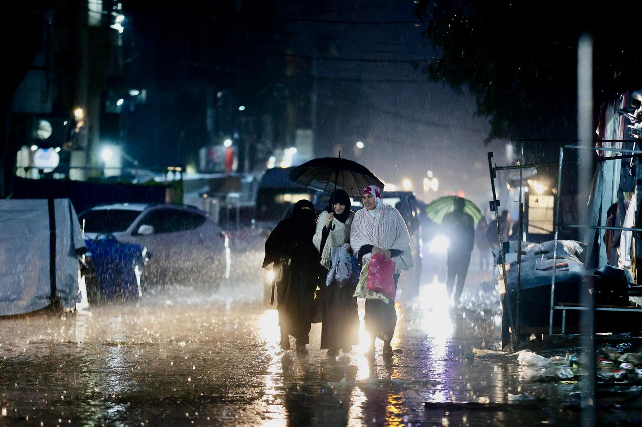 Displaced Palestinians use umbrellas to shield from the rain in Gaza City on December 15, 2025. (AFP Photo )