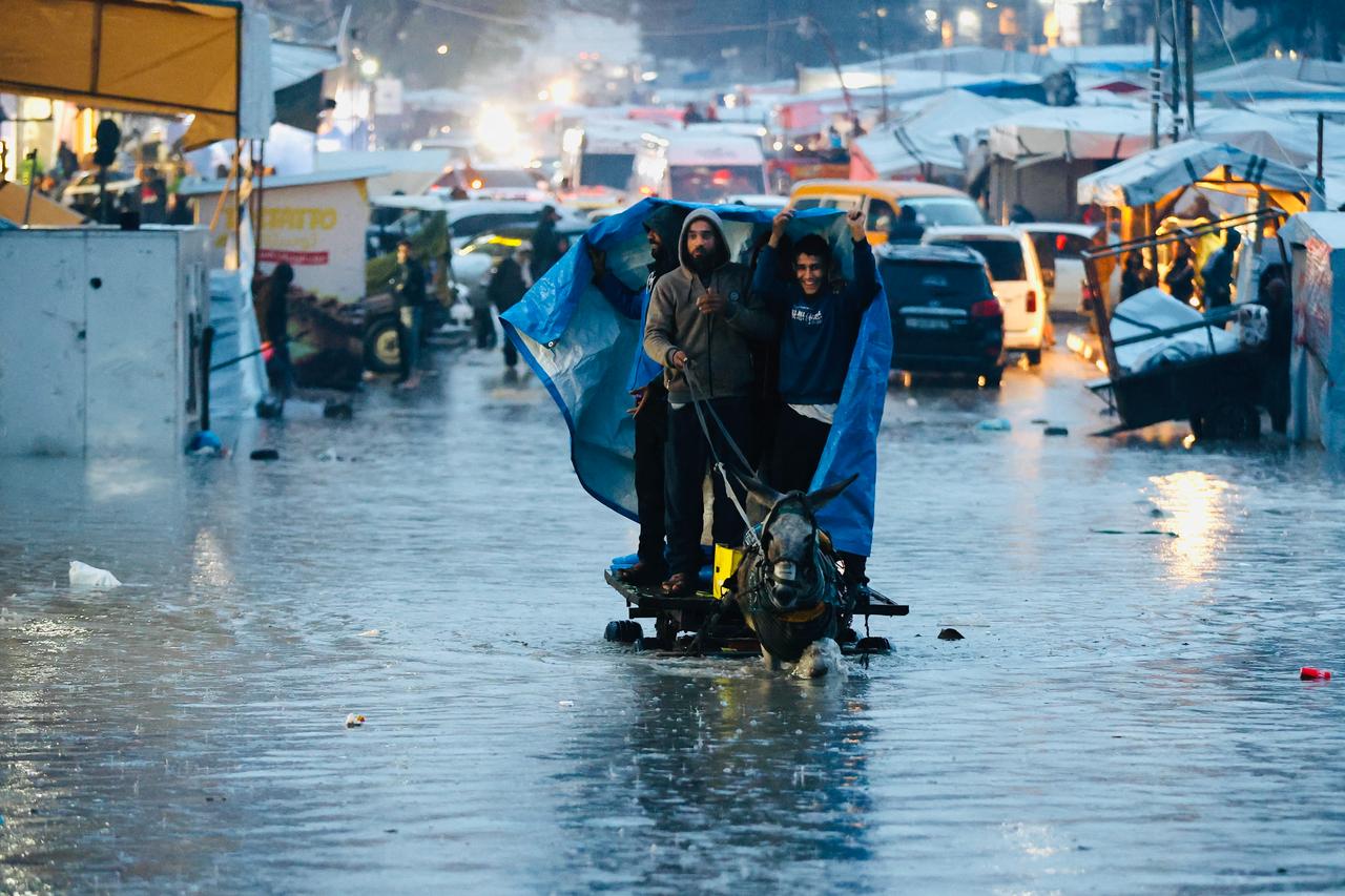 Displaced Palestinians ride on a horse-pulled cart through floodwaters in Gaza City on December 15, 2025. (AFP Photo )