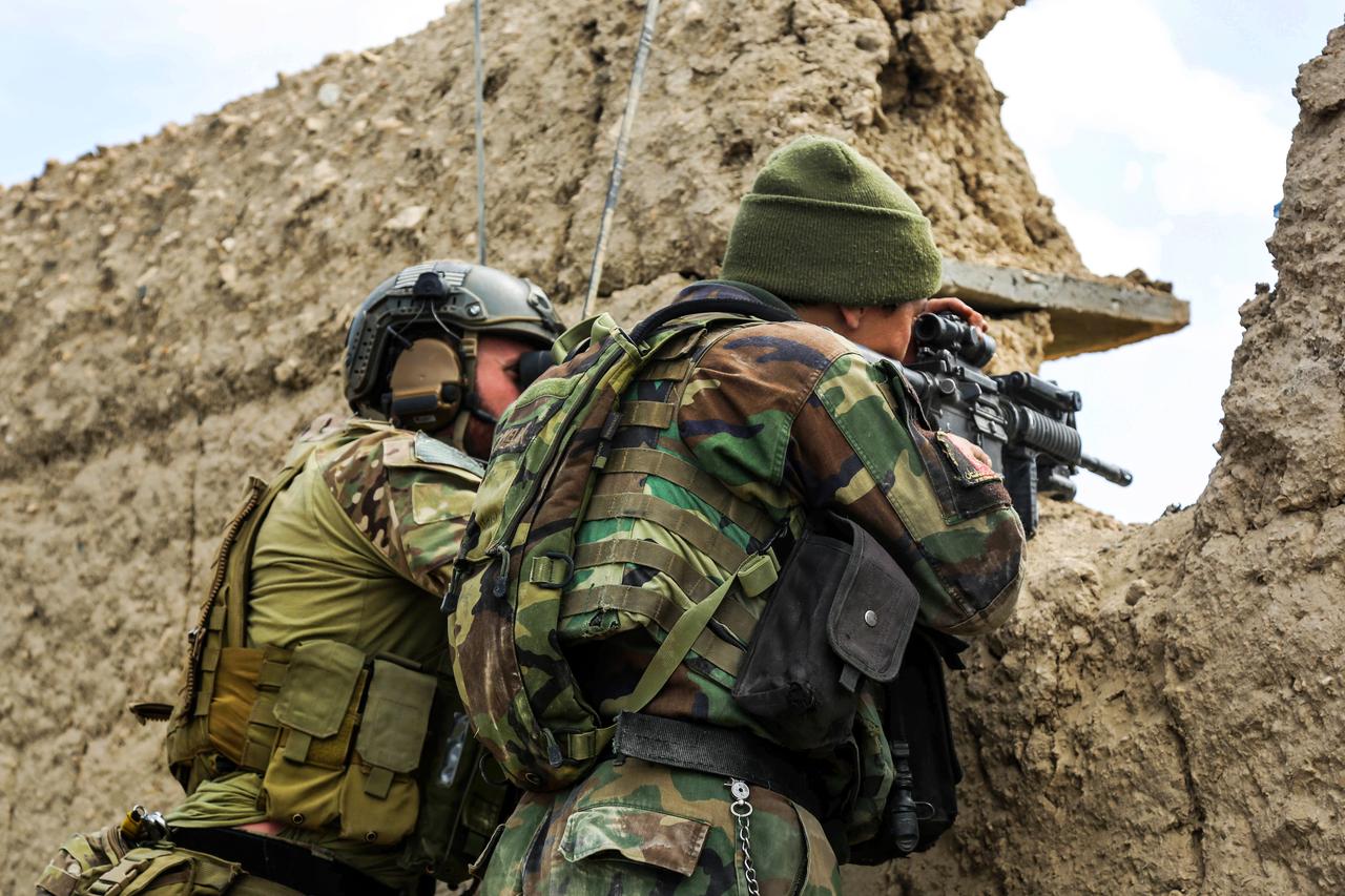 A U.S. Special Forces soldier, left, and an Afghan army commando scan the area for enemy activity after taking fire during a clearing operation in the Khogyani district of Afghanistan's Nangarhar province, March 20, 2014.  (Photo via US DoW)