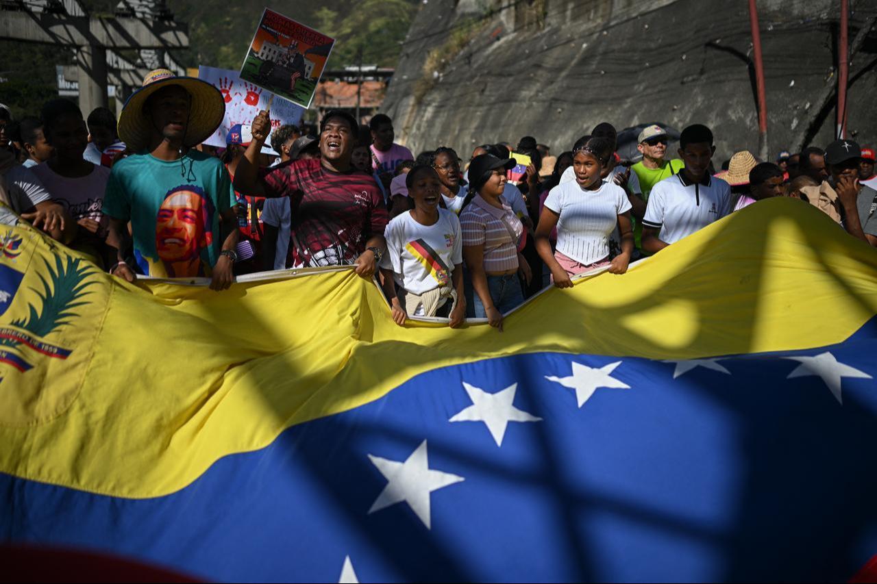 Supporters of Venezuelan President Nicolas Maduro display a giant Venezuelan flag as they take part in a rally against US military activity in the Caribbean, in Caracas, Dec. 13, 2025. (AFP Photo)