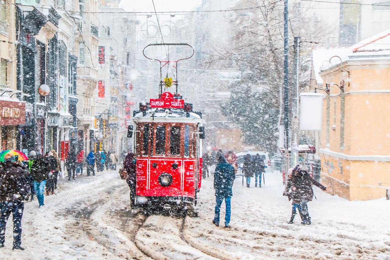 The red tram is moving through the snow on Istiklal Street. (Adobe Stock Photo)