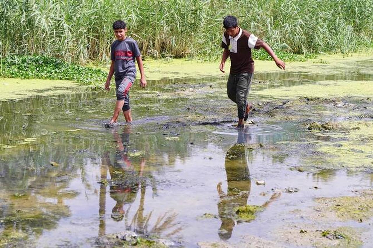 Iraqi children walk in a dried up stream in Najaf province, Iraq. (AFP Photo )