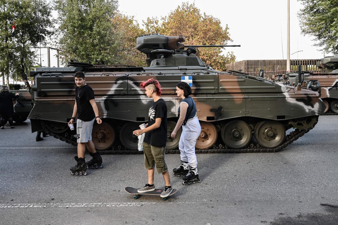 Youngs with rollers and a skateboard pass next to a Marder 1A3, an infantry fighting vehicle, before a military parade in Thessaloniki, Greece, on Oct. 28, 2022. (AFP Photo)
