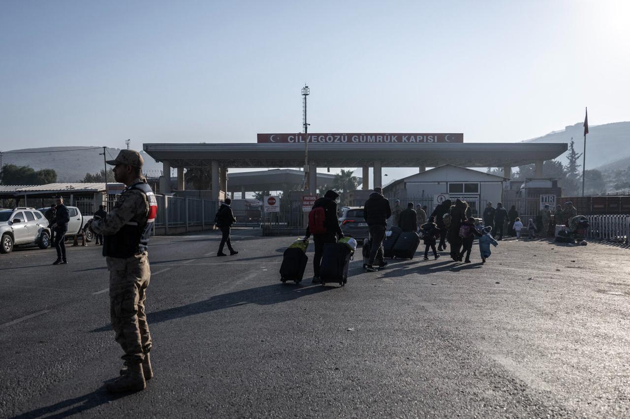 Syrian refugees who live in Türkiye walk with their belongings at the Cilvegozu cross-border gate before entering Syria at the Reyhanli district in Hatay on Dec. 9, 2024. (AFP Photo)