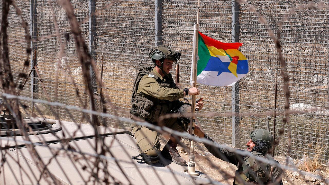 Israeli army soldiers fix a Druze flag attached to the antenna of an army humvee at a position along the barbed-wire fence near the Druze village of Majdal Shams in the Israel-annexed Golan Heights, July 19, 2025. (AFP Photo)
