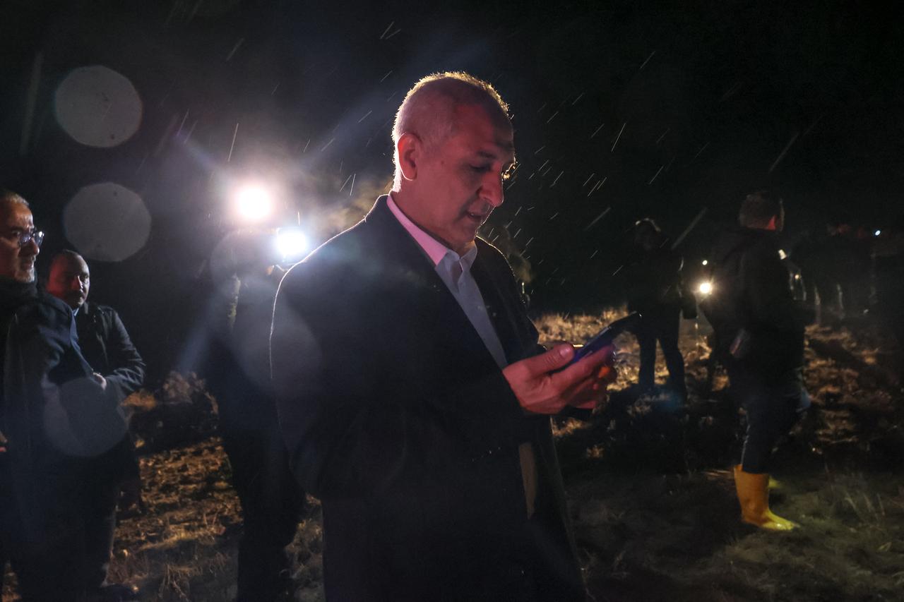 Mostafa E.M Elgelaib, Ambassador of Libya to Türkiye, looks to his mobile phone as search and rescue operations are ungoing at the wreckage site in Ankara, Dec. 24, 2025. (AFP Photo)
