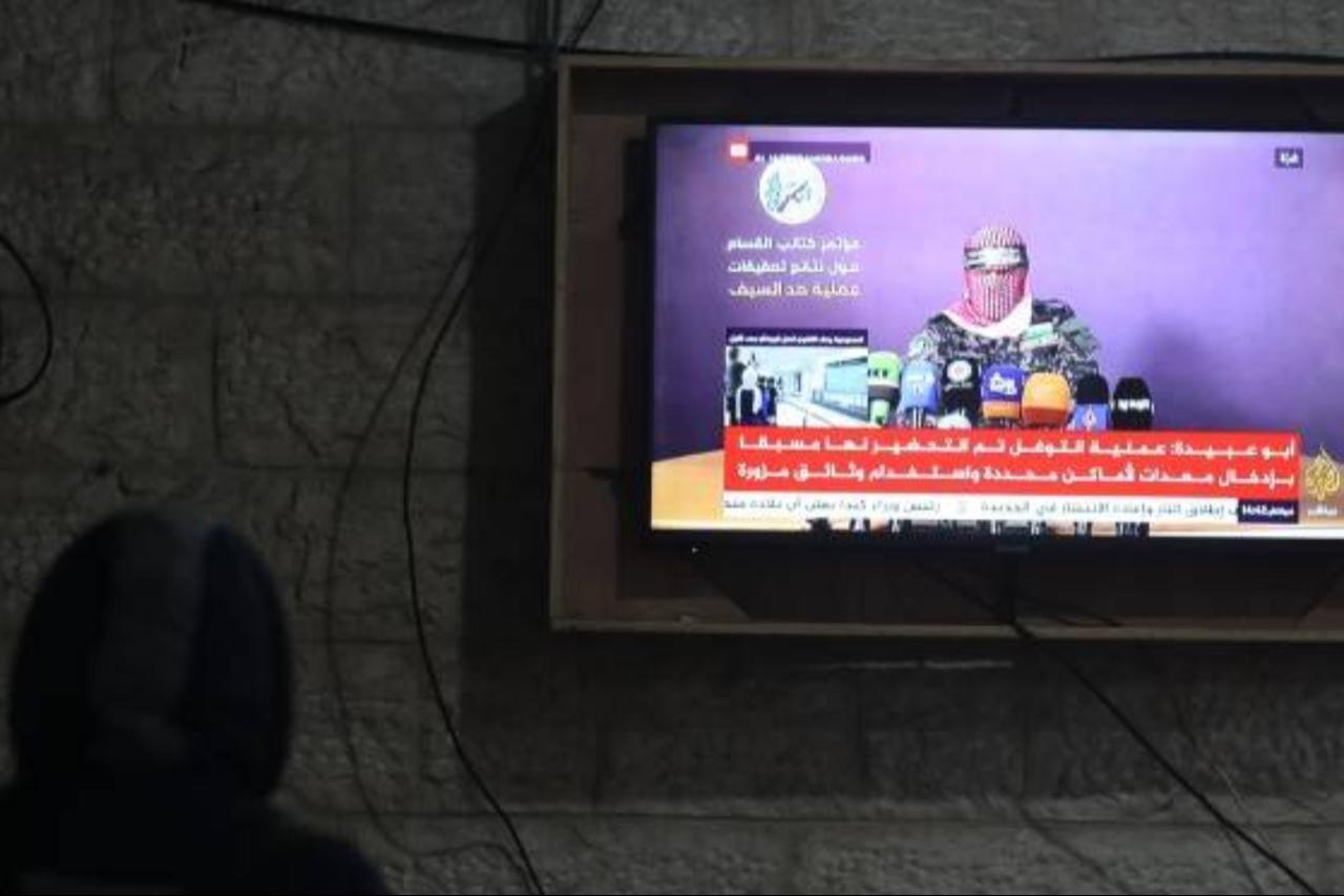 People watch Abu Obaida, the spokesman for the Ezzedine Al-Qassam Brigades, the armed wing of Hamas, during a news conference on a television screen in Gaza City on 12 January 2019. (AFP photo)