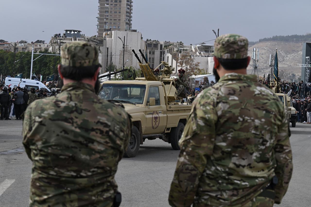 Military vehicles drive past people gathering to celebrate a year since the ousting of longtime ruler Bashar al-Assad in the Syrian capital Damascus, Dec. 8, 2025. (AFP Photo)
