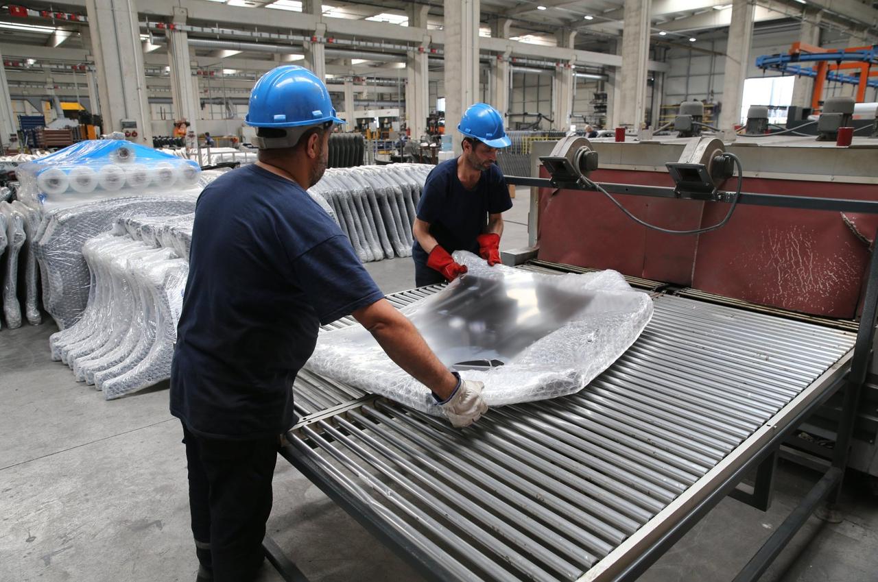 Workers handle a metal automotive component at a vehicle parts manufacturing plant in Türkiye. (AA Photo)
