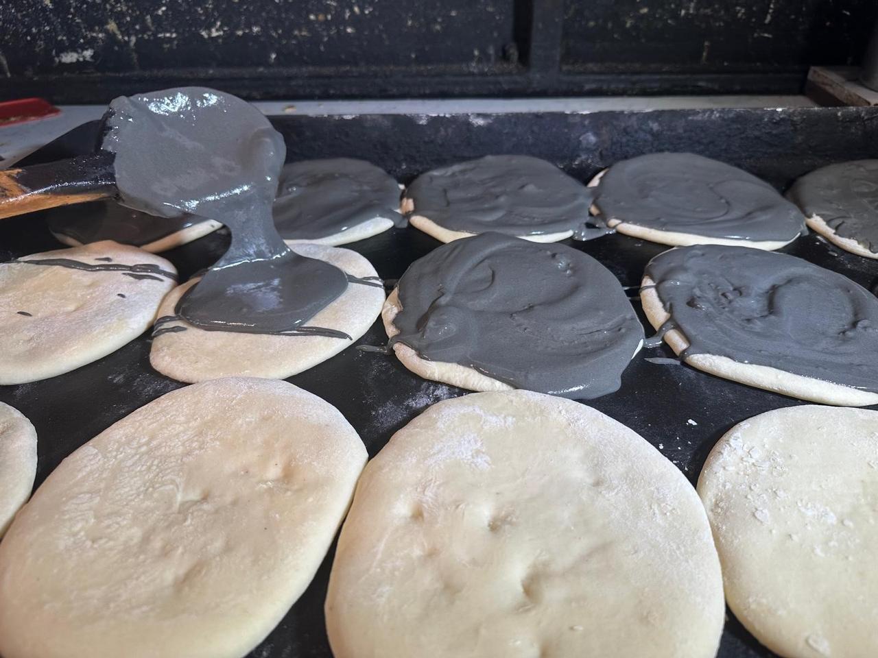 Black sesame tahini sourced from Peru is poured onto dough before baking at a historic bakery in Bursa, Türkiye, Dec. 2, 2025. (IHA Photo)