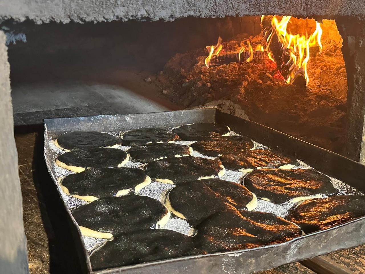 Trays of black-tahini pides bake inside a wood-fired stone oven at a historic bakery in Bursa, Türkiye, Dec. 2, 2025. (IHA Photo)