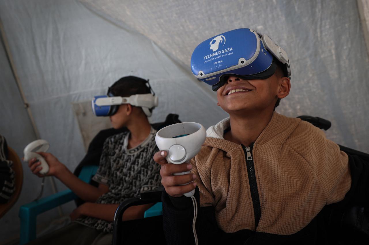 Palestinian children wearing goggles and holding a joystick experience virtual reality as a medical technology support team launches an initiative in the city of Al-Zawayda, in the central Gaza Strip, on November 30, 2025. (AFP photo)