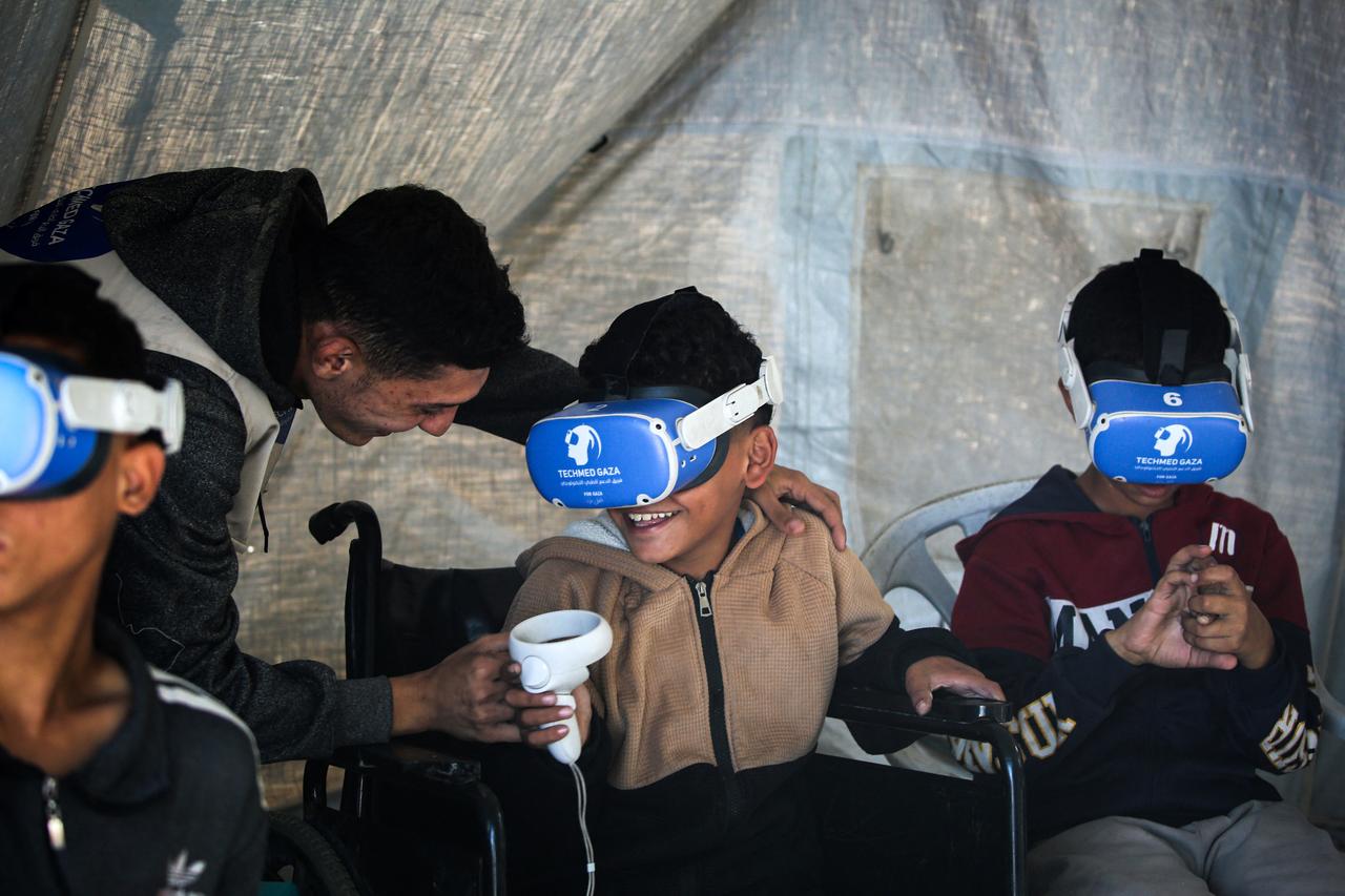 Palestinian children wearing goggles and holding a joy stick experience virtual reality as a medical technology support team launches an initiative featuring therapy sessions using virtual reality technology in the city of Al-Zawayda, in the central Gaza Strip, on November 30, 2025. (AFP Photo)
