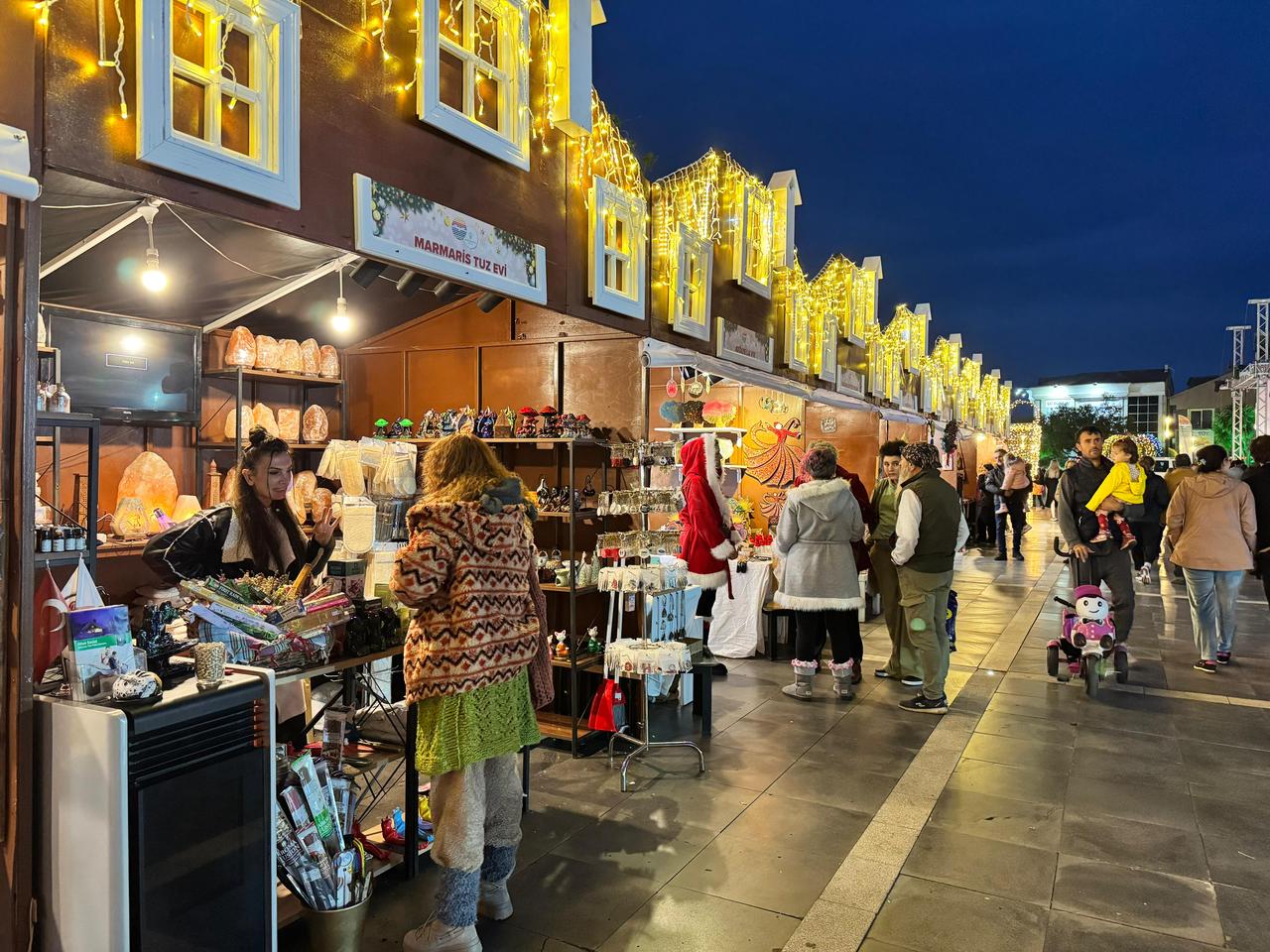 Families stroll through brightly lit food and gift stalls lined along the festival area in central Marmaris, Mugla, Türkiye, Dec. 2, 2025. (AA Photo)