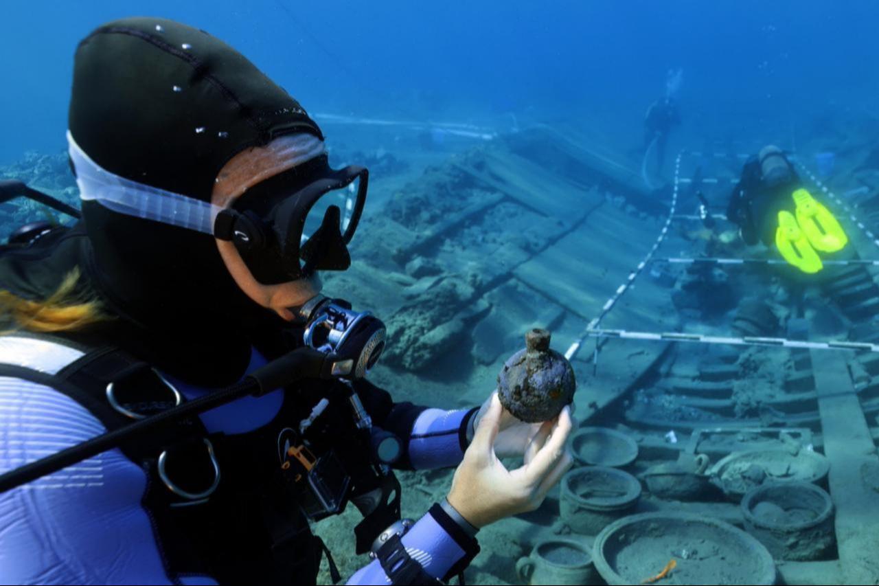 A diver examines an artifact recovered from the 17th-century Ottoman shipwreck during underwater excavations in the Mediterranean, Aug. 24, 2025. (AA Photo)