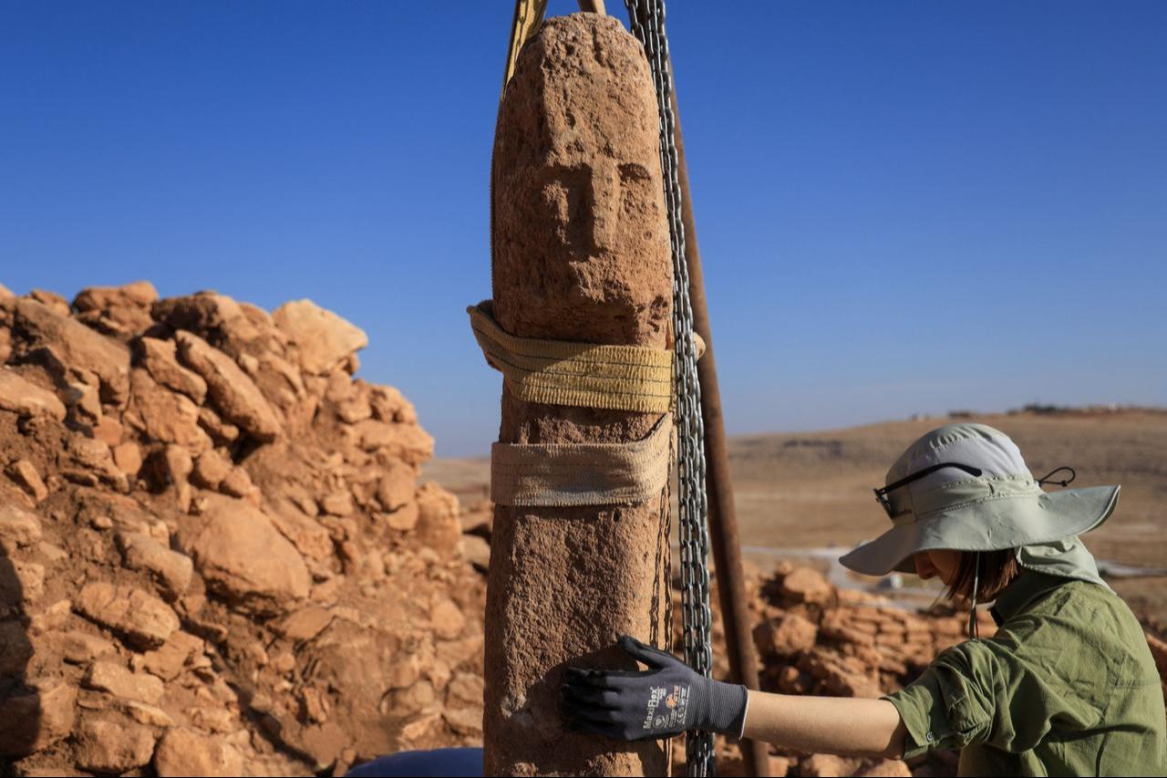 An archaeologist works on lifting a newly unearthed T-shaped pillar carved with a human face at Karahantepe, one of the sites of the Tas Tepeler Project in southeastern Türkiye, Oct. 6, 2025. (AA Photo)