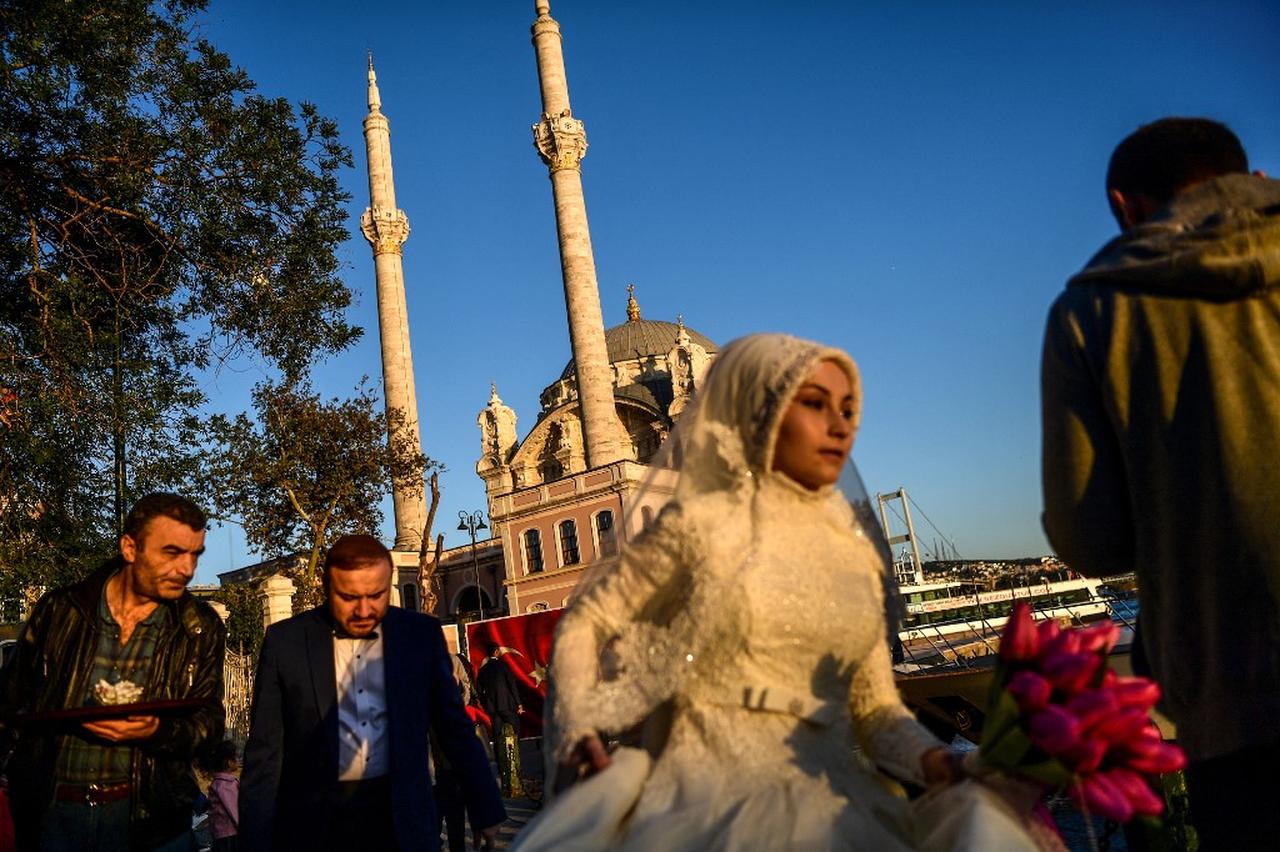 A bride and groom walk as they get ready for wedding pictures on October 17, 2017 at the Ortakoy district in Istanbul. (AFP Photo)