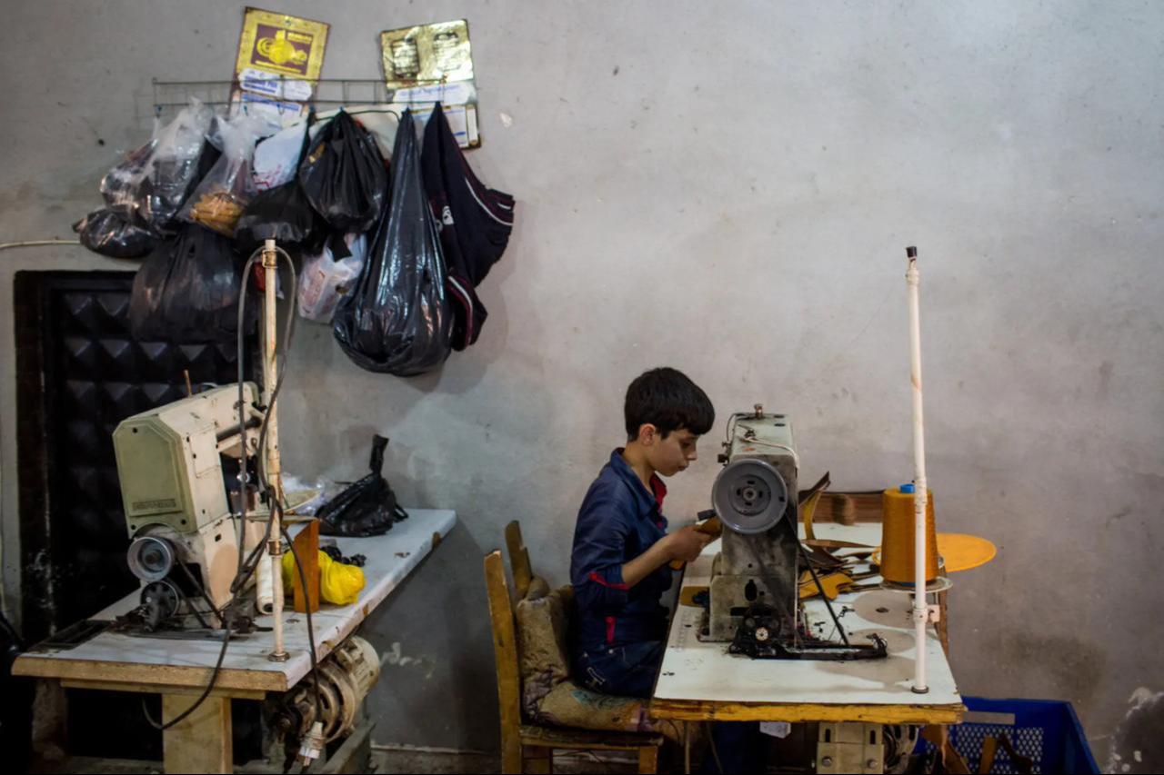 A young Syrian refugee sewed shoe parts in a factory in Gaziantep, Türkiye, 2016. (Photo via Chris McGrath)