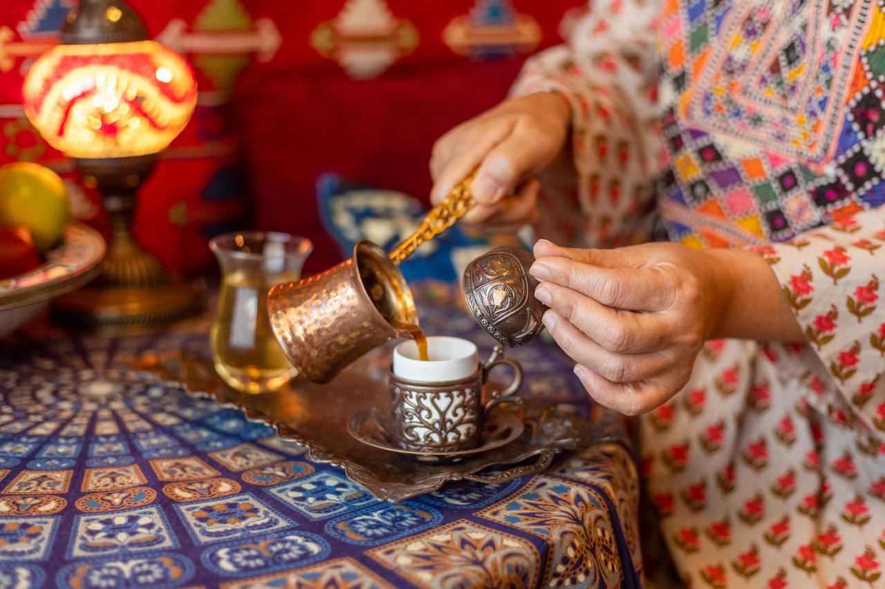 A traditional cezve is used to pour freshly brewed Turkish coffee into an ornate cup as part of a centuries-old serving ritual. (Adobe Stock Photo)