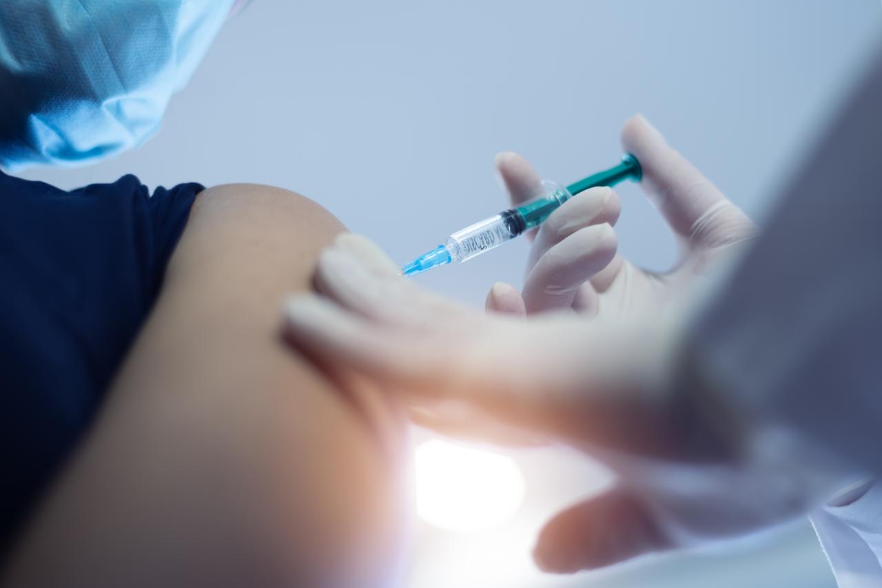 Doctor preparing to administer a COVID-19 vaccine into a patient’s arm. (Adobe Stock Photo)
