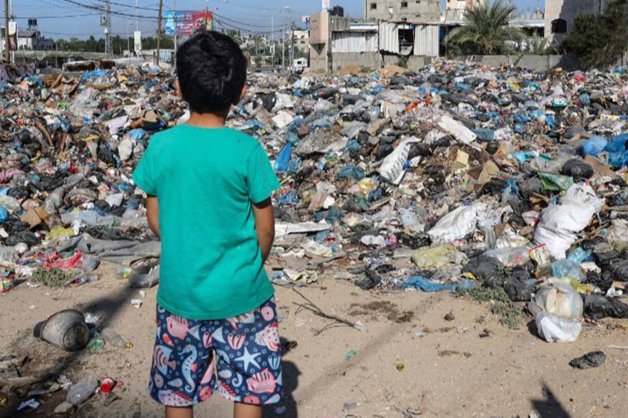 A boy looks at piles of rubbish littering the Bureij camp for Palestinian refugees, Nov. 4, 2023. (AFP Photo)