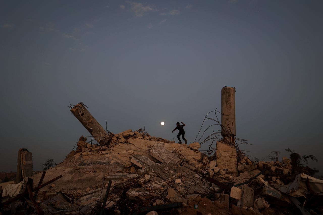 A youth plays on the rubble of a destroyed building as the Cold Moon, the last supermoon of the year, rises over the Nuseirat camp for displaced Palestinians in the central Gaza Strip on Dec. 4, 2025. (AFP Photo)