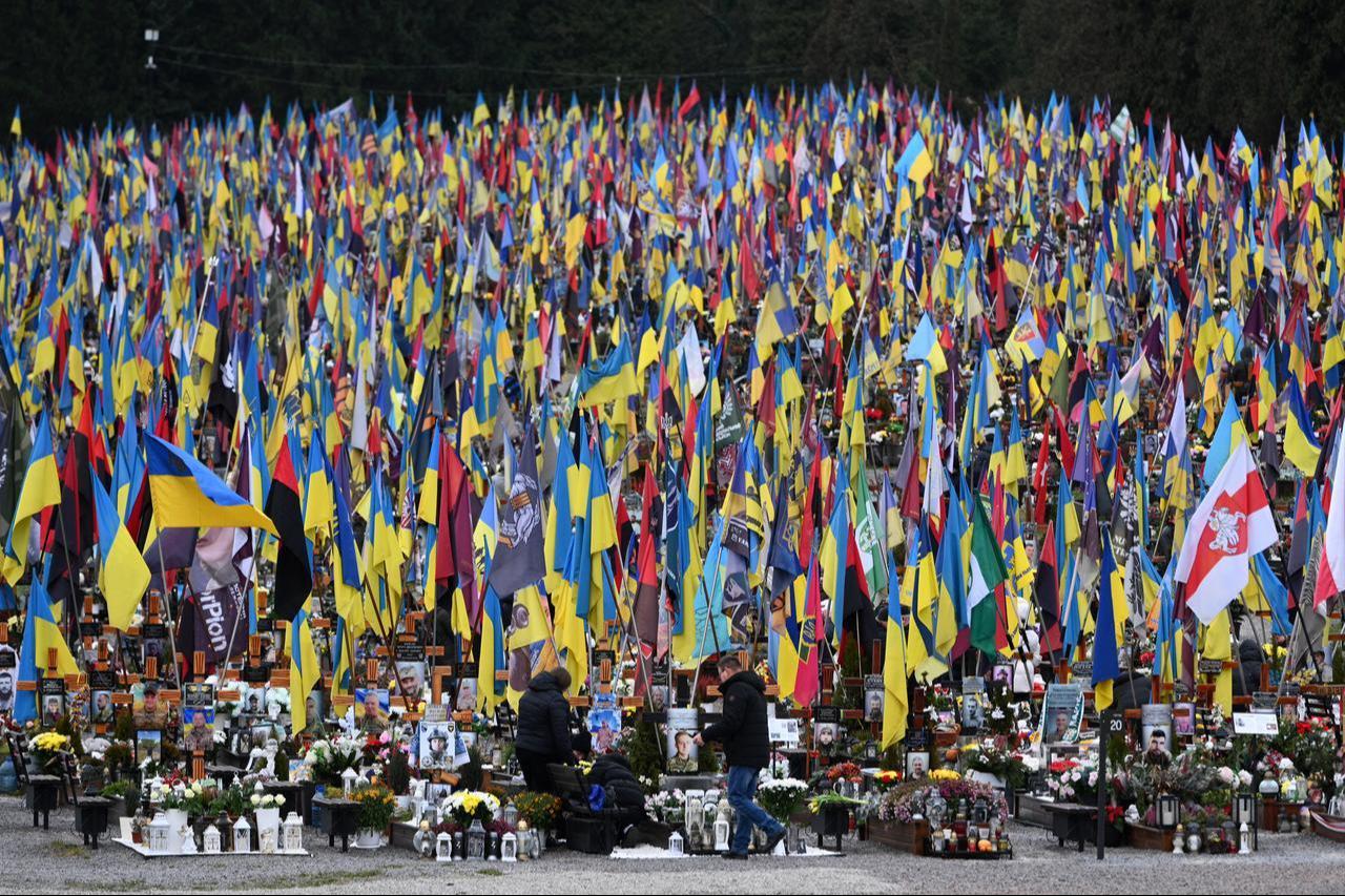 People mourn at the graves of Ukrainian servicemen at the Lychakiv cemetery on the Day of the Armed Forces of Ukraine, in Lviv, December 6, 2025. (AFP Photo)